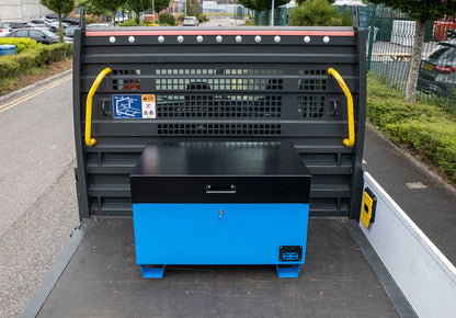 Large blue metal tool box closed with a black lid on the back of a flat bed truck.