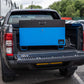 Large blue metal tool box closed with a black lid on the back of a 4x4 pick up truck.
