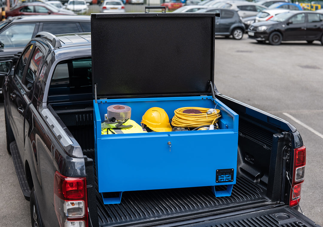 Large blue metal tool box  with a range of electrical tools inside and a yellow hard hat. The toolbox is on the back of a pick up van.