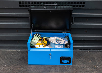 Small blue metal tool box  with a range of electrical tools inside and a yellow hard hat. The toolbox is on the back of a pick up van.