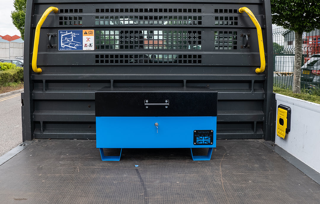 Blue metal tool box closed with a black lid on the back of a flat bed truck.