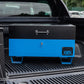 Blue metal tool box closed with a black lid on the back of a 4x4 pick up truck.