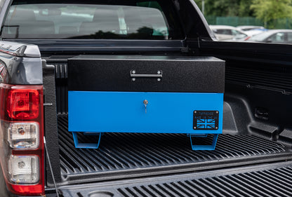 Blue metal tool box closed with a black lid on the back of a 4x4 pick up truck.